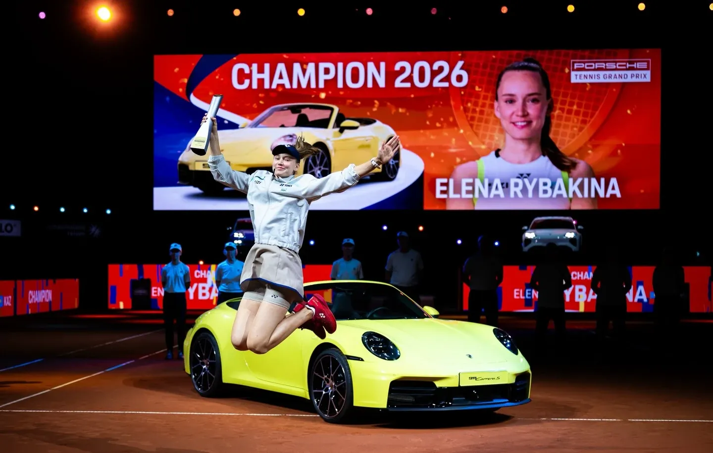 Елена Рыбакина на фоне Porsche 911 Carrera S Cabriolet на церемонии награждения турнира в Штутгарте в апреле 2026 года.